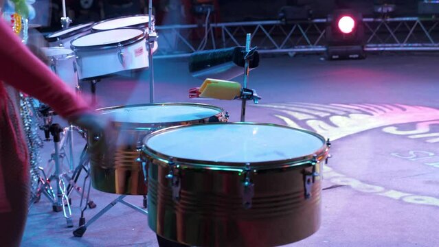 Close-up of drummers in sexy costumes performing in the circus arena in the light of colorful spotlights and smoke. Circus drum show with concert lighting. Dancers perform with drums in a circus.