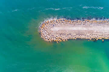 Obraz premium Aerial top view of a groyne on a beach, breakwater for harbor protection