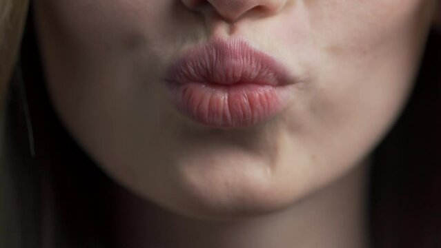 Close-up of a woman's lips sending an air kiss. Beautiful pink lips of a young Caucasian girl. perfect background for cosmetology