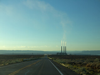 Ecology concept with distant power plant in the desert landscape, smoke rising from the chimney
