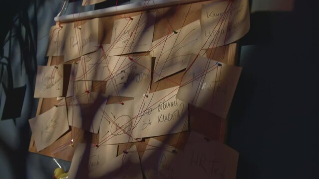 Mysterious notes with threads. Stock footage. Blackboard with notes and red threads in mysterious office. Riddle of puzzles on board with notes and threads