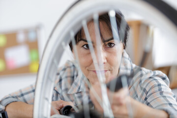 mature happy positive woman master is repairing bicycle in workshop