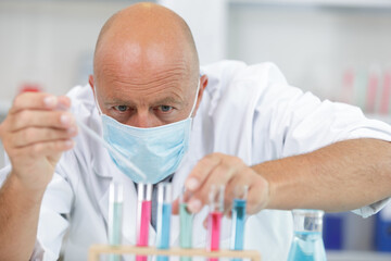 scientist with mouth-mask using pippete in lab
