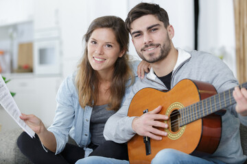 a couple playing guitar on couch indoor