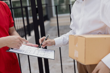 A young man hands a cardboard box to a young woman while standing in front of her house.
Hold a...