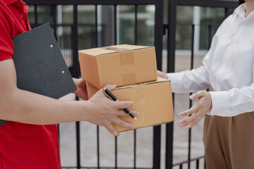 A young man hands a cardboard box to a young woman while standing in front of her house.
Hold a...