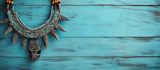 A tribal ethnic necklace is featured in a still life arrangement on light blue painted wood creating a visually appealing copy space image