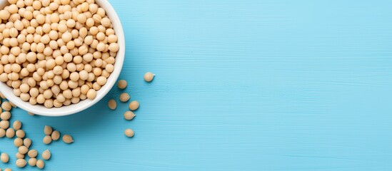 A top down view of a bowl containing soy beans on a blue table with plenty of space for additional images