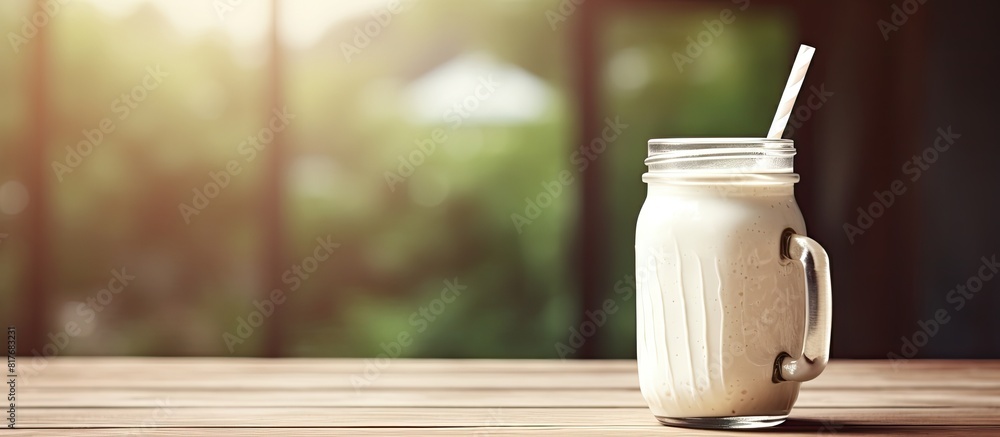 Poster Copy space image of a delicious milkshake served in a charming mason jar complete with a straw placed on a rustic wooden table