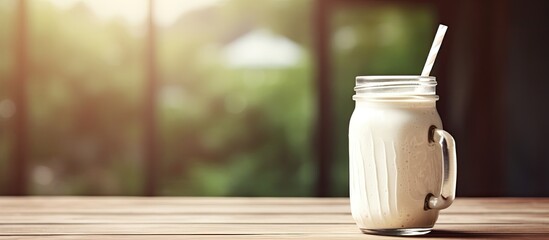 Copy space image of a delicious milkshake served in a charming mason jar complete with a straw placed on a rustic wooden table