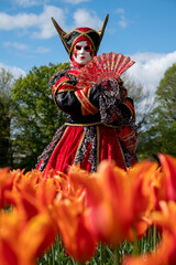 Fototapeta premium Venetian carnival character in a park with flowers