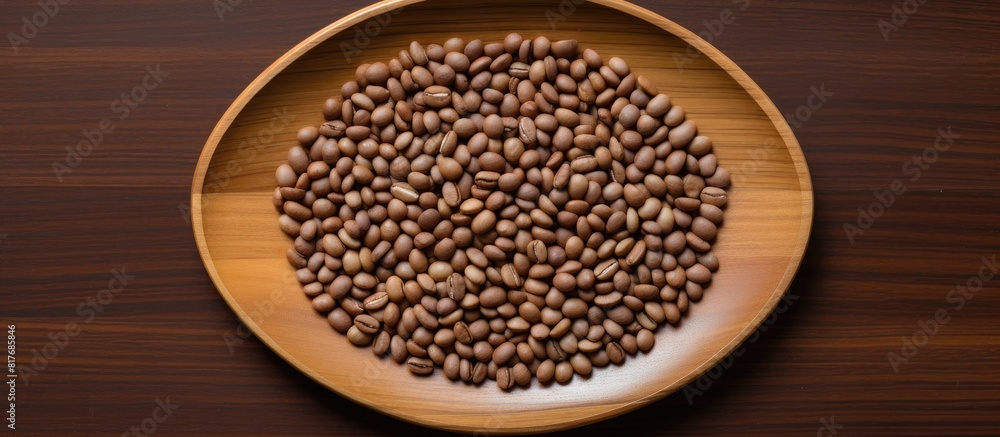 Poster A top down view of a cluster of coffee seeds arranged on a bamboo plate surrounded by a wooden table with empty space for further items. Creative banner. Copyspace image