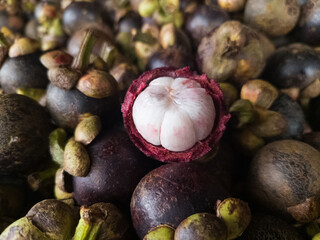 pile of mangosteen fruit. fruit that has purple skin and white flesh