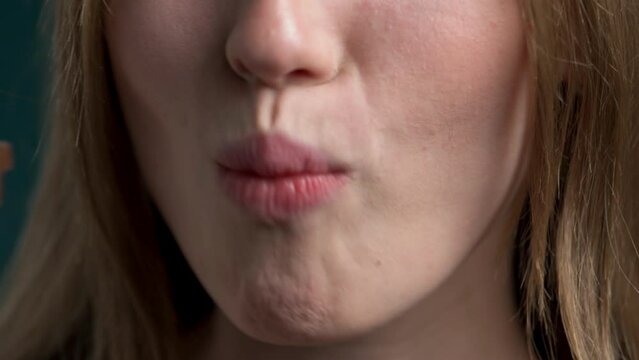 he cropped face of one real girl consumes a candy bar as a lunchtime snack. Playful human woman with sweet fast food in her cute cute mouth. beautiful pink plump lips closeup
