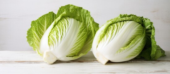 Table with a white wooden background showcasing fresh ripe Chinese cabbage both whole and cut Copy space image