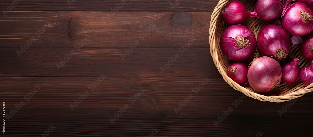 Aufkleber A wooden background frames a top down view of a basket brimming with whole and cut red onions creating a perfect copy space image