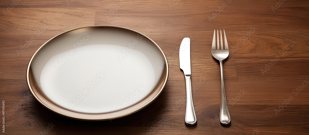 Poster An eating concept is depicted in the image of a spoon and fork alongside a white dish placed on a wooden table with copy space