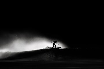 Minimalistic black and white image capturing the dynamic motion of a female surfer riding a wave