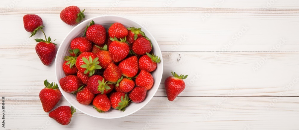 Poster Top view copy space image of a white wooden background with a heap of fresh strawberries in a bowl