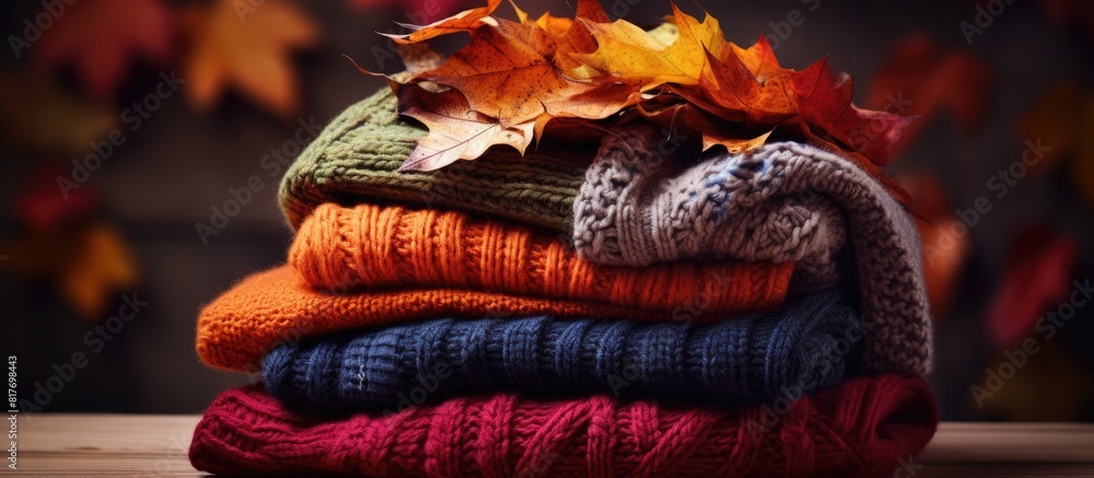 Poster An image featuring a pile of knitted sweaters complemented by the vibrant colors of autumn leaves in a close up copy space image