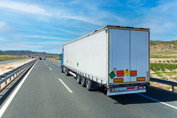 Large tonnage truck traveling on a highway with license plates and labels for dangerous goods, non-flammable gases under pressure and oxidizing material. Category 5.1 in ADR.