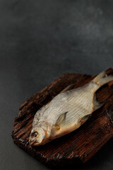 Dried bream fish on a cutting board on a black background
