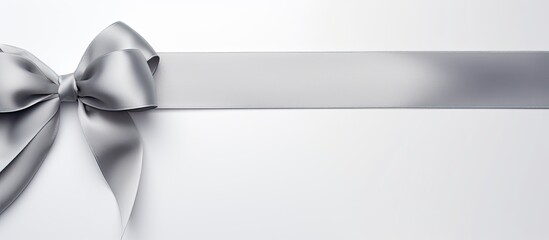 A silver silk ribbon featuring a lovely bow is showcased on a white background in this captivating copy space image