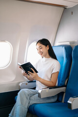 Asian woman sitting in a seat in airplane and looking out the window going on a trip vacation travel concept.Capture the allure of wanderlust .