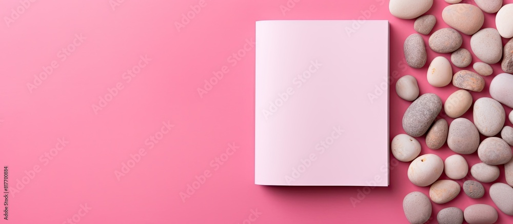 Poster A pink background with a pebble on it serves as a colorful surface for a top view of a blank notebook with ample copy space