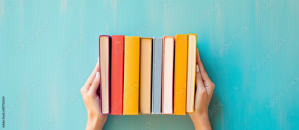 Poster Female hands holding books on a colorful background creating a visually appealing copy space image