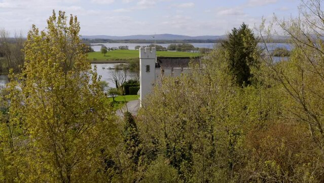Cargin castle revealed behind trees to Lough Corrib, aerial dolly