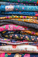 A stack of colorful quilts, with different fabric patterns and textures.