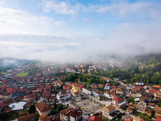 Bulgaria - 05 22 2024: Mini 2 capturing the beautiful morning light with vibrant blue sky and foggy clouds covering the village and the forest, with the beautiful golden mosque in the center.