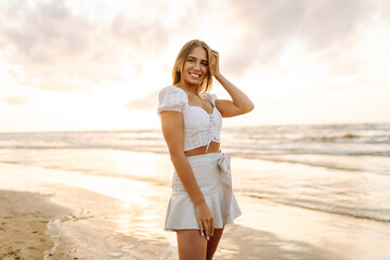 Young woman enjoying looking view of beach ocean on summer day at sunset. Travel, weekend, relax and lifestyle concept. 