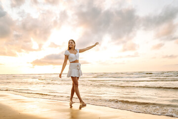 Young woman enjoying looking view of beach ocean on summer day at sunset. Travel, weekend, relax and lifestyle concept. 