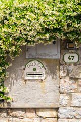 Mailbox nestled on stone wall with vibrant flowers cascading around it against the rustic brickwork backdrop