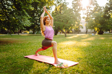 Young woman in sportswear stretching body on fitness mat at public park, doing yoga. Healthy lifestyle, sport. Fitness. Woman doing yoga in morning park.