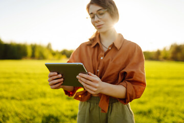 Woman Farmer  with tablet analysing  and control of plant quality in the soil smart digital agriculture. Green young wheat field.