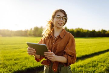 Woman Farmer  with tablet analysing  and control of plant quality in the soil smart digital agriculture. Green young wheat field.