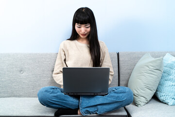 自宅でノートパソコンを使う若い女性
