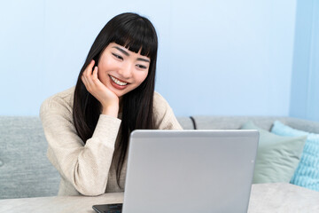 自宅でノートパソコンを使う若い女性