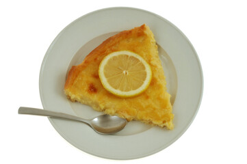 Part de tarte au citron dans une assiette avec une cuillère vue de dessus en gros plan sur fond blanc
