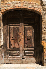close up of an ancient wooden door with iron details, set within a rustic stone arch, embodying old world charm