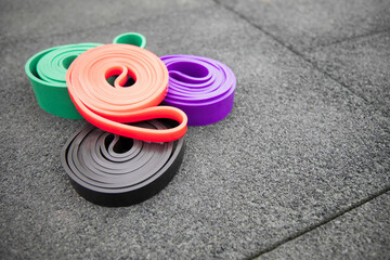 set of colorful elastic fitness bands  on sport ground. Outdoor workouts concept . Copy space