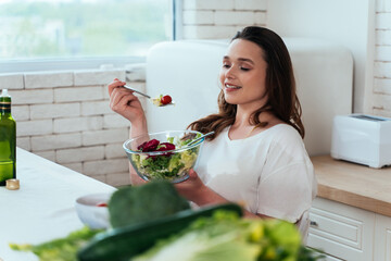 Lifestyle moments of a young woman at home. Woman enjoying a salad and healthy food in the kitchen.