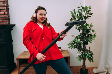 Woman playing the vacuum pretending to be a guitar for fun.