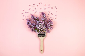 Top view of purple lilac flowers on pink background. Creative paintbrush composition. Spring...
