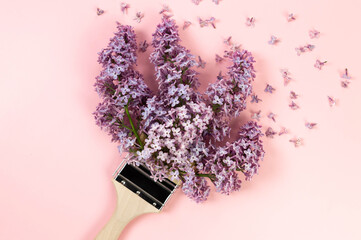 Top view of purple lilac flowers on pink background. Creative paintbrush composition. Spring...
