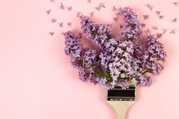 Top view of purple lilac flowers on pink background. Creative paintbrush composition. Spring wallpaper, flat lay, copy space.
