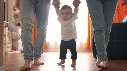 baby takes his first steps. happy family a kid dream concept. parents teaching child to walk...